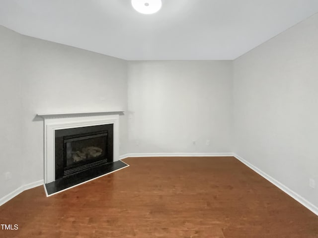 unfurnished living room with a fireplace, baseboards, and wood finished floors