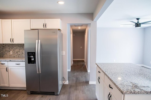 kitchen with light stone counters, stainless steel refrigerator with ice dispenser, backsplash, and white cabinetry