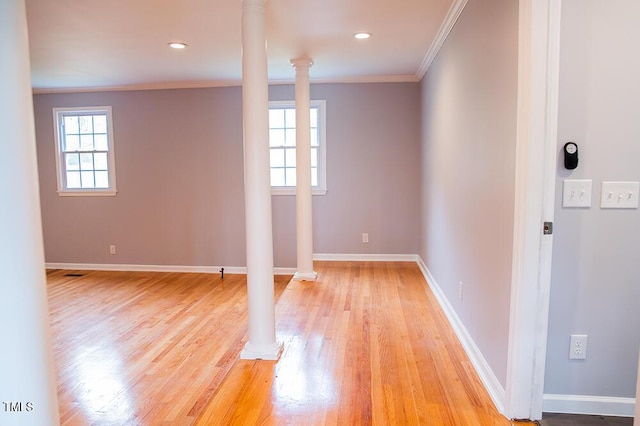 unfurnished room with ornamental molding, light wood-style flooring, decorative columns, and baseboards