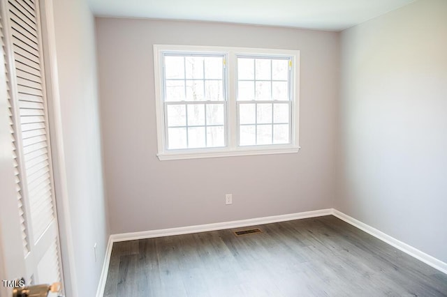 unfurnished room with visible vents, baseboards, and wood finished floors