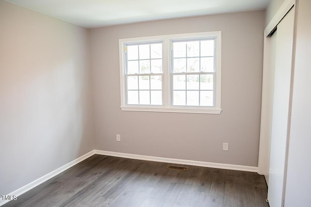 unfurnished bedroom with dark wood-type flooring, visible vents, and baseboards