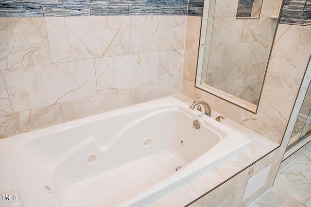 bathroom with marble finish floor and a tub with jets