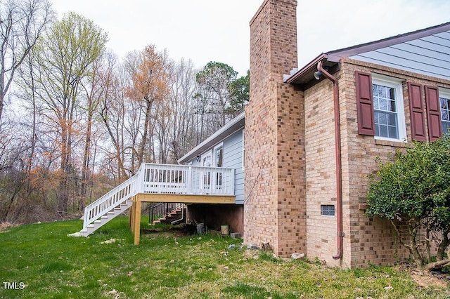 view of side of property with stairs, a chimney, a deck, and a lawn