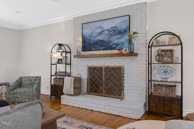 living area with a brick fireplace, crown molding, and wood finished floors