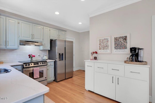 kitchen featuring tasteful backsplash, light wood-style floors, ornamental molding, stainless steel appliances, and under cabinet range hood