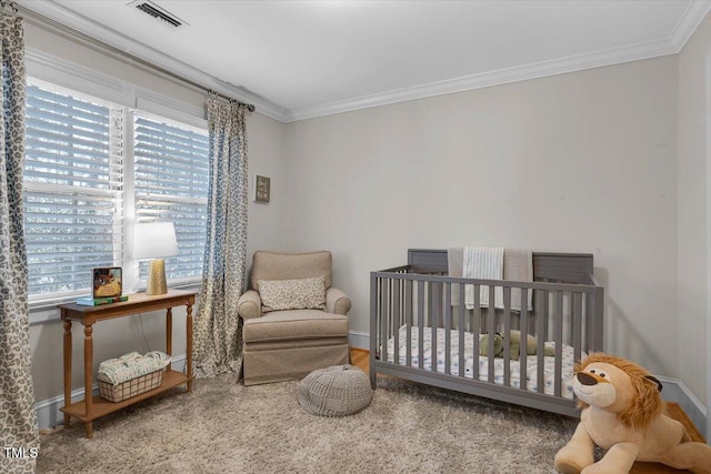 bedroom with ornamental molding, visible vents, a crib, and baseboards