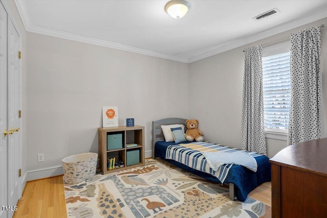 bedroom featuring baseboards, crown molding, visible vents, and wood finished floors