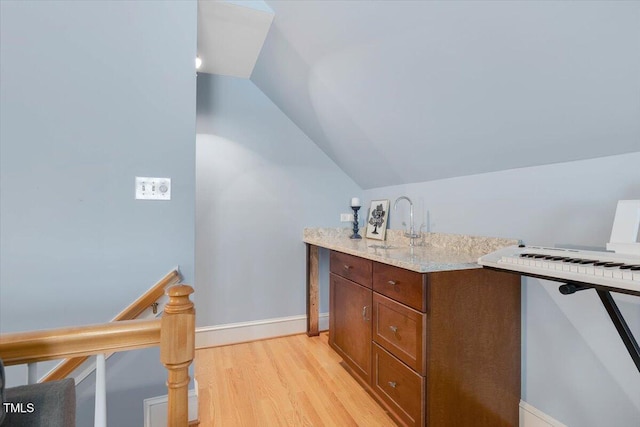 bathroom with a sink, vaulted ceiling, baseboards, and wood finished floors