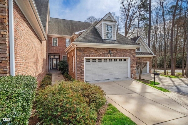 view of front facade with an attached garage, stone siding, concrete driveway, and brick siding