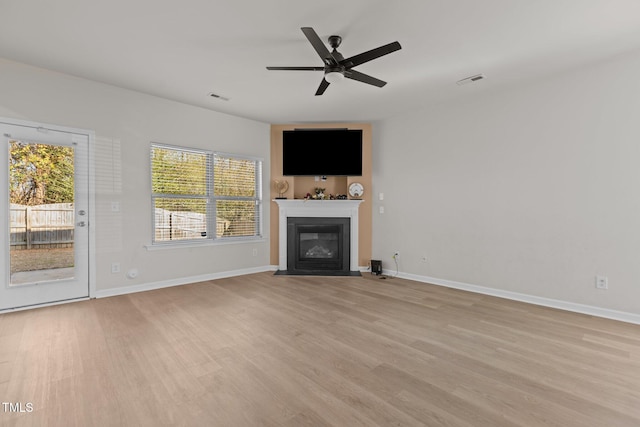 unfurnished living room featuring light wood-type flooring, a fireplace with flush hearth, baseboards, and a ceiling fan