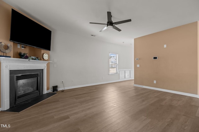 unfurnished living room with visible vents, a ceiling fan, a glass covered fireplace, wood finished floors, and baseboards