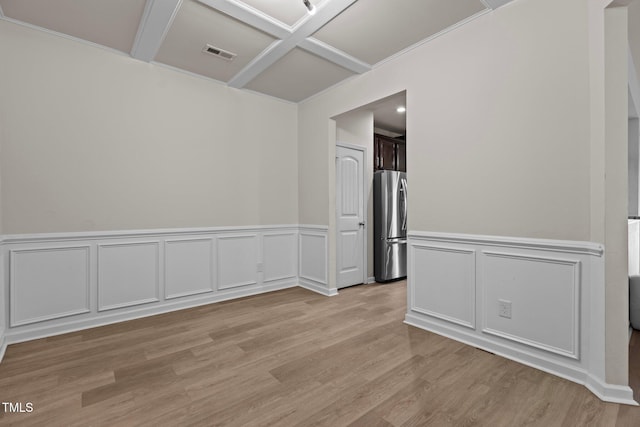 spare room with light wood-style flooring, visible vents, coffered ceiling, and a decorative wall