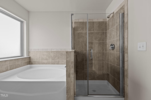 bathroom featuring a shower stall and a bath