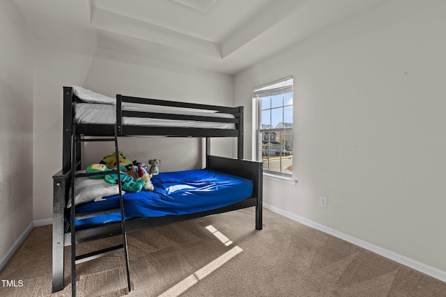 bedroom featuring carpet floors, a raised ceiling, and baseboards