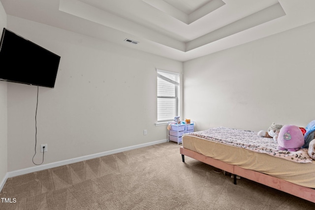 bedroom featuring carpet floors, a tray ceiling, visible vents, and baseboards