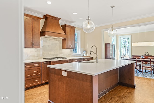 56 Mist Wood Ct, Pittsboro, NC 27312 - kitchen featuring custom exhaust hood, light wood-type flooring, light countertops, a kitchen island with sink, and stainless steel gas stovetop