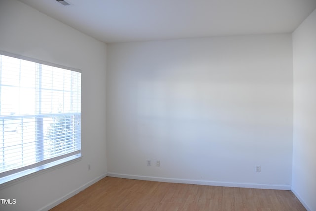 spare room with baseboards and light wood finished floors