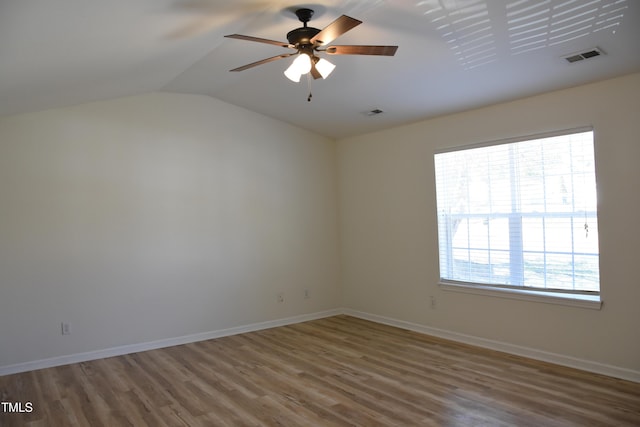 spare room with vaulted ceiling, wood finished floors, visible vents, and baseboards