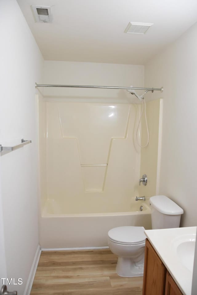 bathroom featuring visible vents, shower / bathing tub combination, toilet, vanity, and wood finished floors