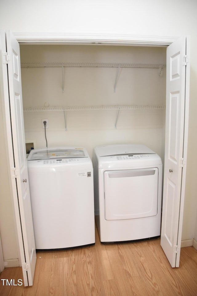 laundry room with laundry area, independent washer and dryer, and light wood-style floors