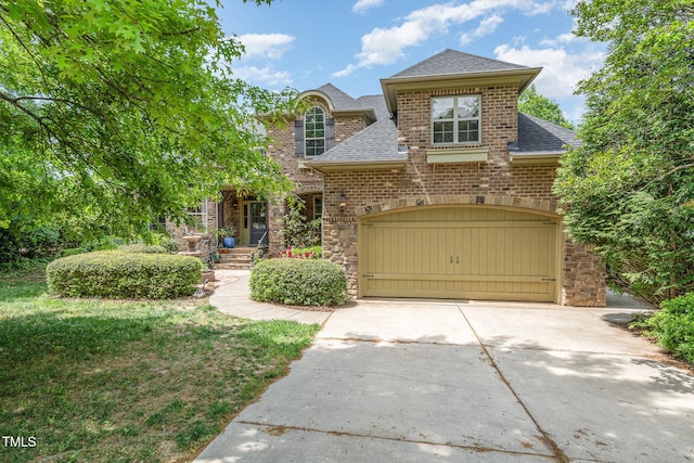 view of front facade featuring stone siding, concrete driveway, an attached garage, a shingled roof, and brick siding