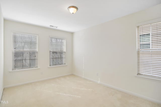 unfurnished room featuring light carpet, visible vents, and baseboards