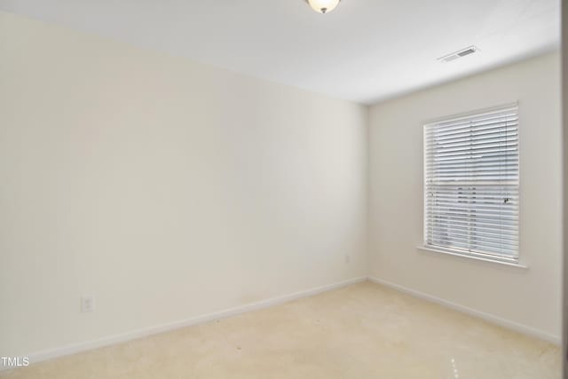 spare room featuring visible vents, light carpet, and baseboards