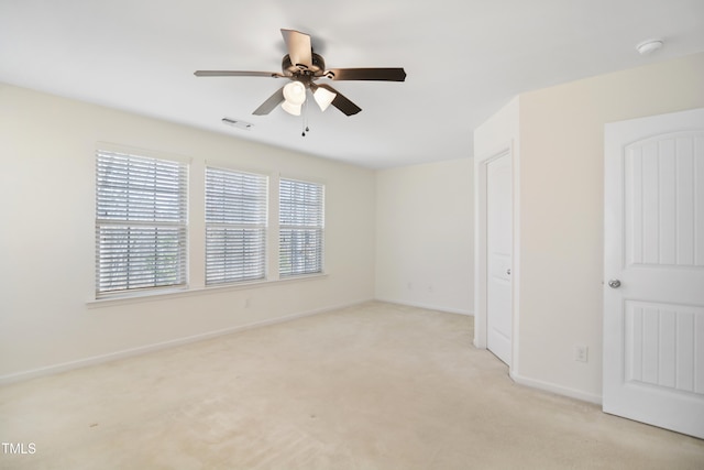 empty room with light carpet, ceiling fan, visible vents, and baseboards