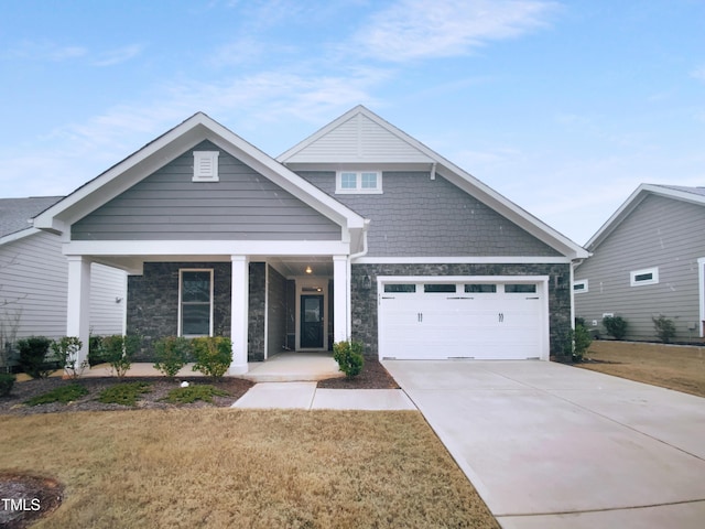 view of front of house with concrete driveway, a front lawn, an attached garage, and stone siding