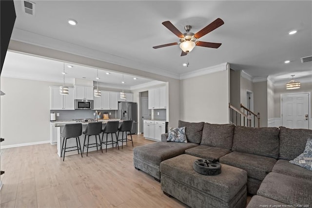 living area with light wood-type flooring, stairs, visible vents, and crown molding