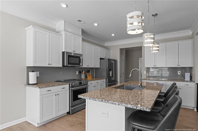 kitchen featuring stainless steel appliances, white cabinets, a kitchen island with sink, and a sink