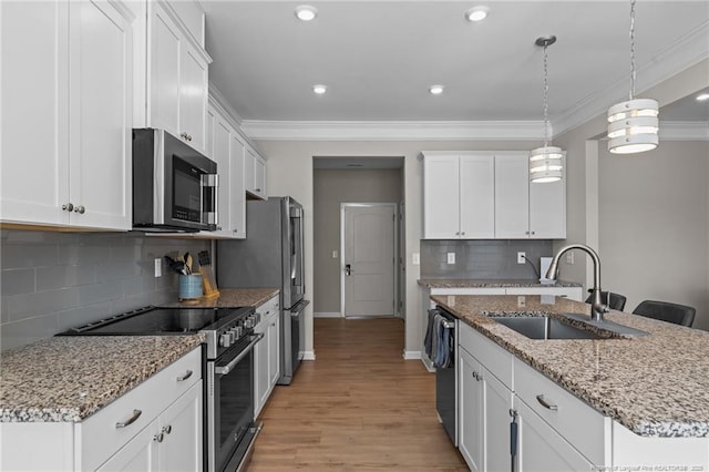 kitchen with stainless steel appliances, white cabinets, hanging light fixtures, and a sink