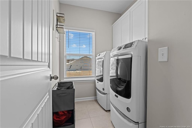 laundry area with baseboards, light tile patterned flooring, cabinet space, and washer and dryer