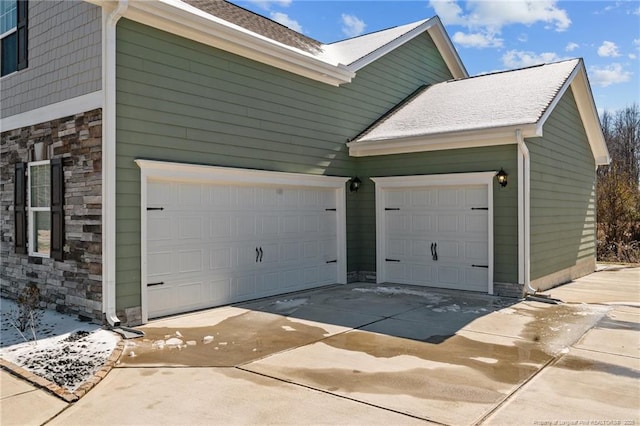 view of home's exterior with an attached garage, stone siding, and concrete driveway