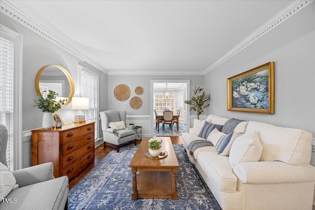 living area featuring a wainscoted wall, ornamental molding, a decorative wall, and wood finished floors