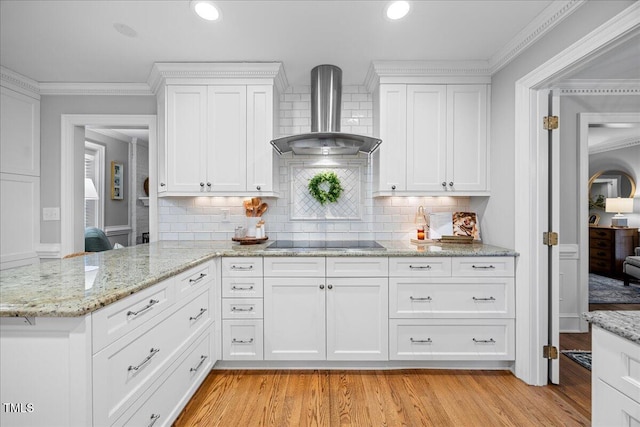 kitchen featuring light wood-style floors, crown molding, wall chimney range hood, and black electric cooktop