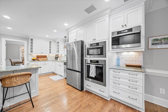 kitchen featuring visible vents, white cabinetry, appliances with stainless steel finishes, light wood finished floors, and glass insert cabinets