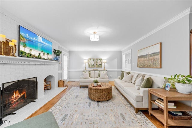 living area featuring baseboards, a fireplace, wood finished floors, and crown molding