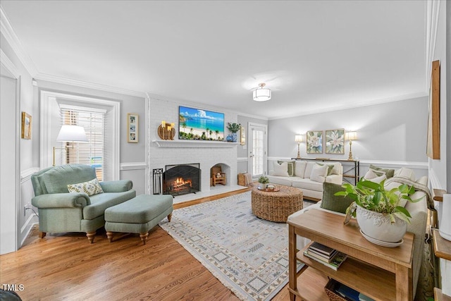 living area with ornamental molding, light wood-type flooring, and a fireplace