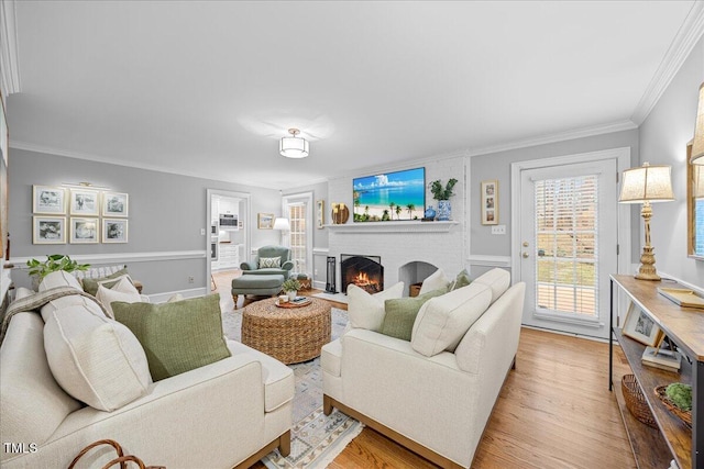 living room with light wood-style floors, a fireplace, and ornamental molding