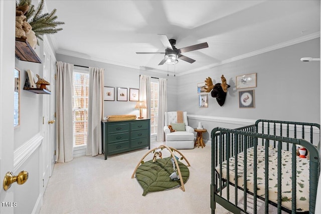 bedroom with ornamental molding, a nursery area, light carpet, and a ceiling fan