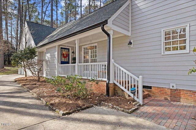 property entrance with crawl space, a shingled roof, and a porch