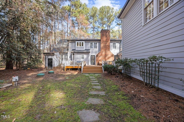 rear view of house featuring a chimney and a wooden deck