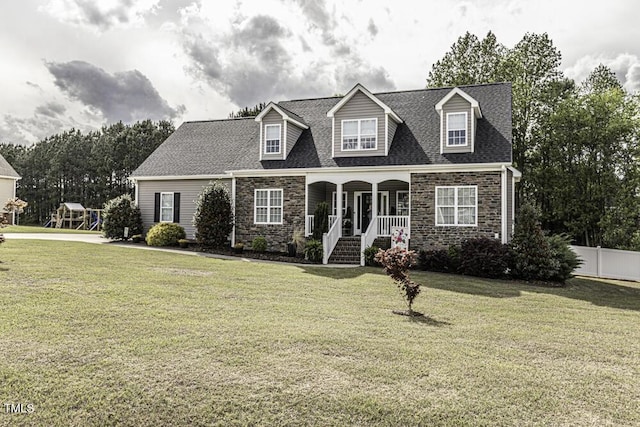 cape cod-style house with a front yard, a porch, stone siding, and fence