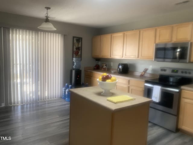 kitchen with appliances with stainless steel finishes, a center island, light countertops, and light brown cabinetry