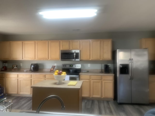 kitchen featuring stainless steel appliances, wood finished floors, light countertops, and light brown cabinetry