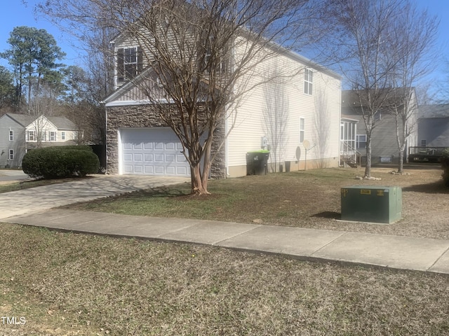 view of side of property with a garage, stone siding, and concrete driveway