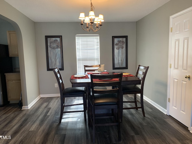 dining room with arched walkways, dark wood-type flooring, a chandelier, and baseboards