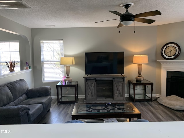 living room featuring a fireplace, wood finished floors, visible vents, and a ceiling fan