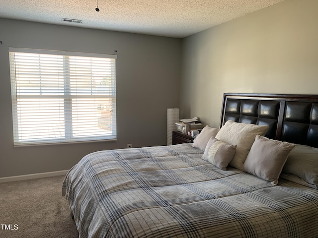 bedroom featuring a textured ceiling, carpet flooring, visible vents, and baseboards